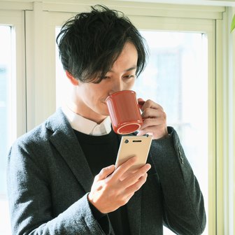 オフィスでコーヒーを片手に社内ラジオを聴く社員