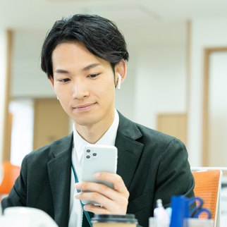 オフィスのデスクでイヤホンを付けて社内ラジオを聴く社員